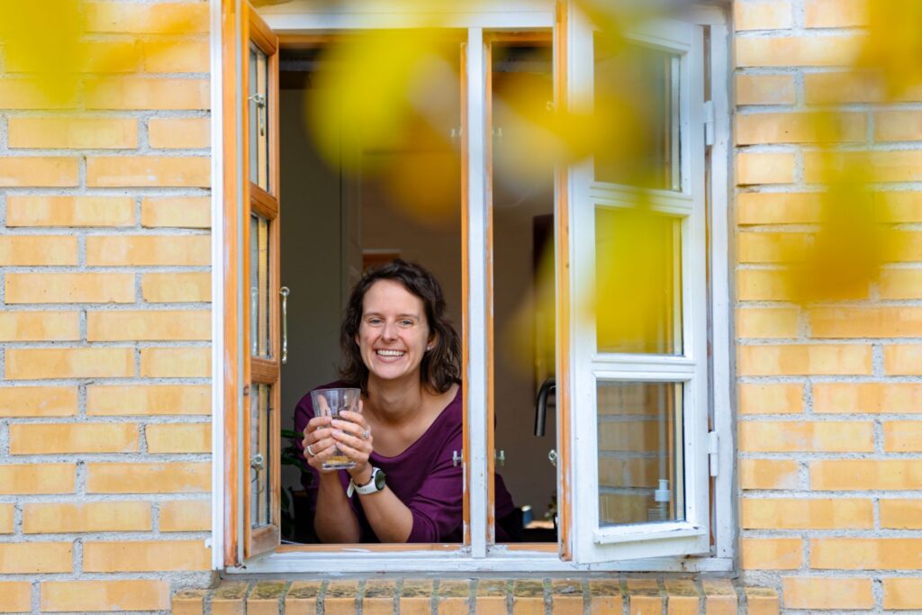 Marlies kijkt uit het raam met een glas thee in haar hand.